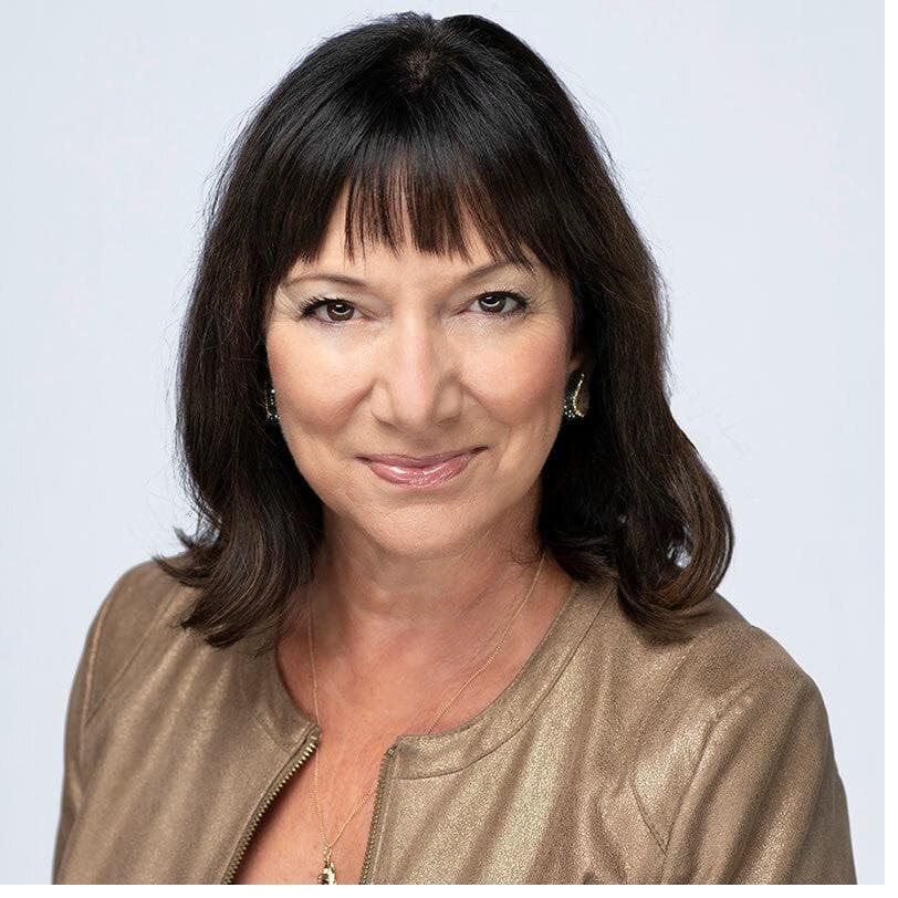Sarina Steinmetz, Sales Vice President at William Raveis, smiling studio headshot in a gold jacket